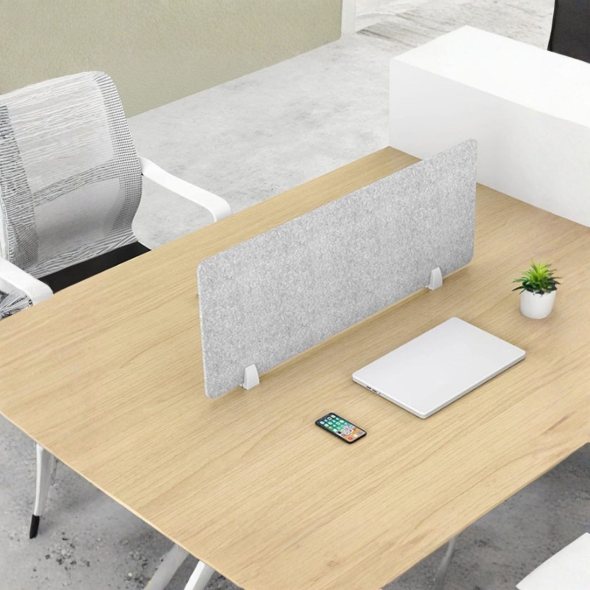 Wooden office desk with a gray partition, smartphone, and tablet on a light gray floor.